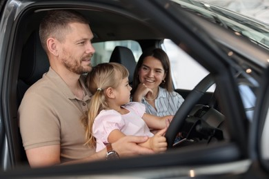Photo of Happy family sitting inside new car. Luxury vehicle