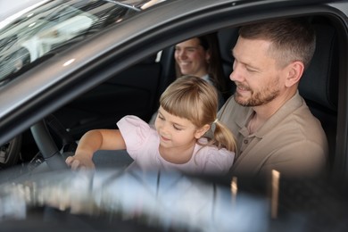 Photo of Happy family sitting inside new car. Luxury vehicle