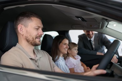 Photo of Happy family inside new car and salesman, selective focus