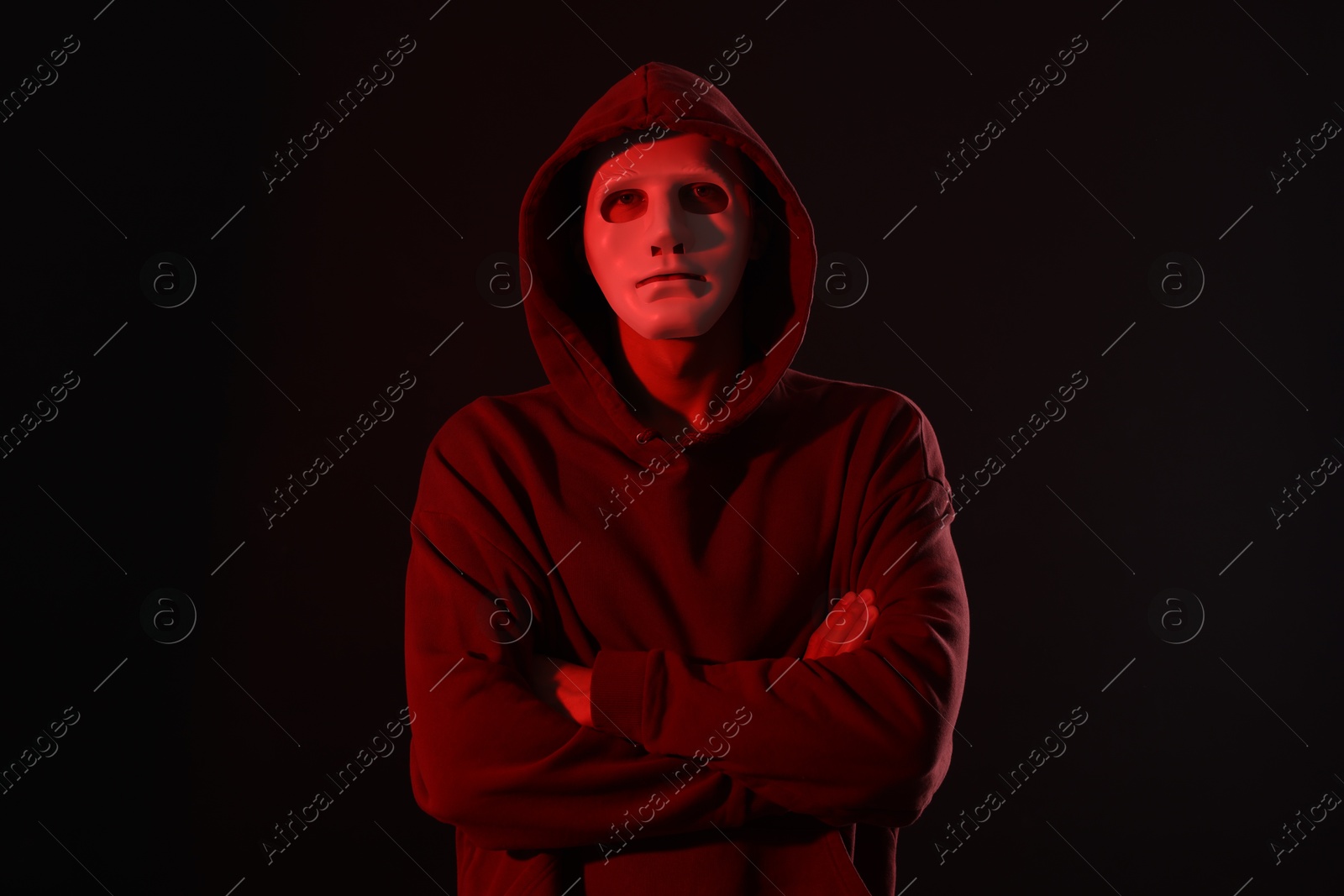 Anonymity. Masked man on dark background with red light Photo of Anonymity. Masked man on dark background with red light