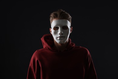 Photo of Anonymity. Man wearing mask on dark background