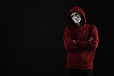 Photo of Anonymity. Man wearing mask on dark background, space for text
