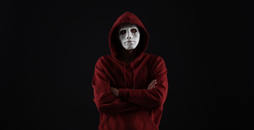 Photo of Anonymity. Man wearing mask on dark background