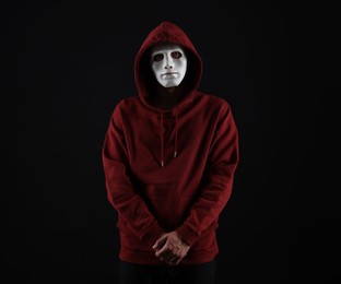 Photo of Anonymity. Man wearing mask on dark background