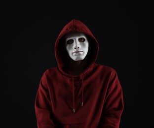 Photo of Anonymity. Man wearing mask on dark background