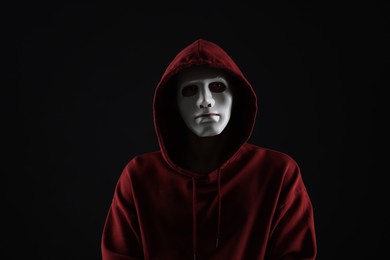 Photo of Anonymity. Man wearing mask on dark background