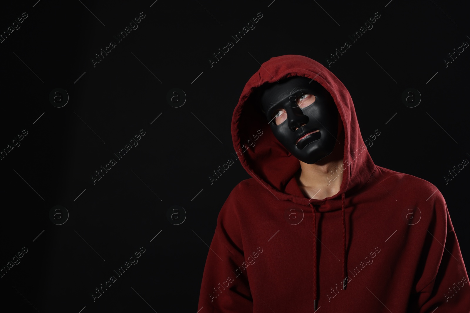 Photo of Anonymity. Man wearing mask on dark background, space for text
