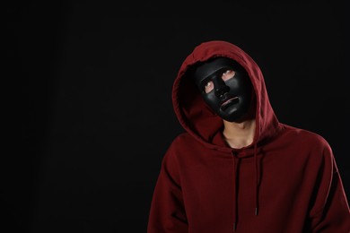Photo of Anonymity. Man wearing mask on dark background, space for text