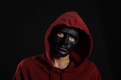 Photo of Anonymity. Man wearing mask on dark background