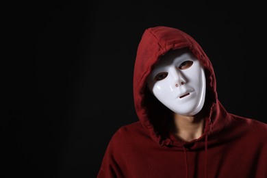 Photo of Anonymity. Man wearing mask on dark background, space for text
