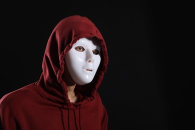 Photo of Anonymity. Man wearing mask on dark background, space for text
