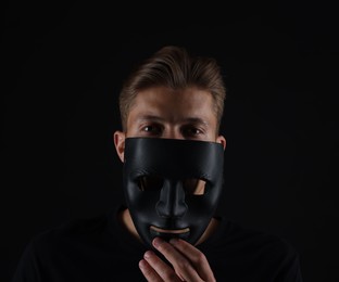 Photo of Anonymity. Man with mask on dark background