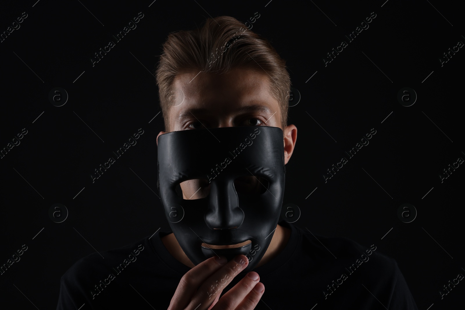 Photo of Anonymity. Man with mask on dark background