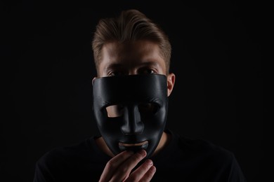 Photo of Anonymity. Man with mask on dark background