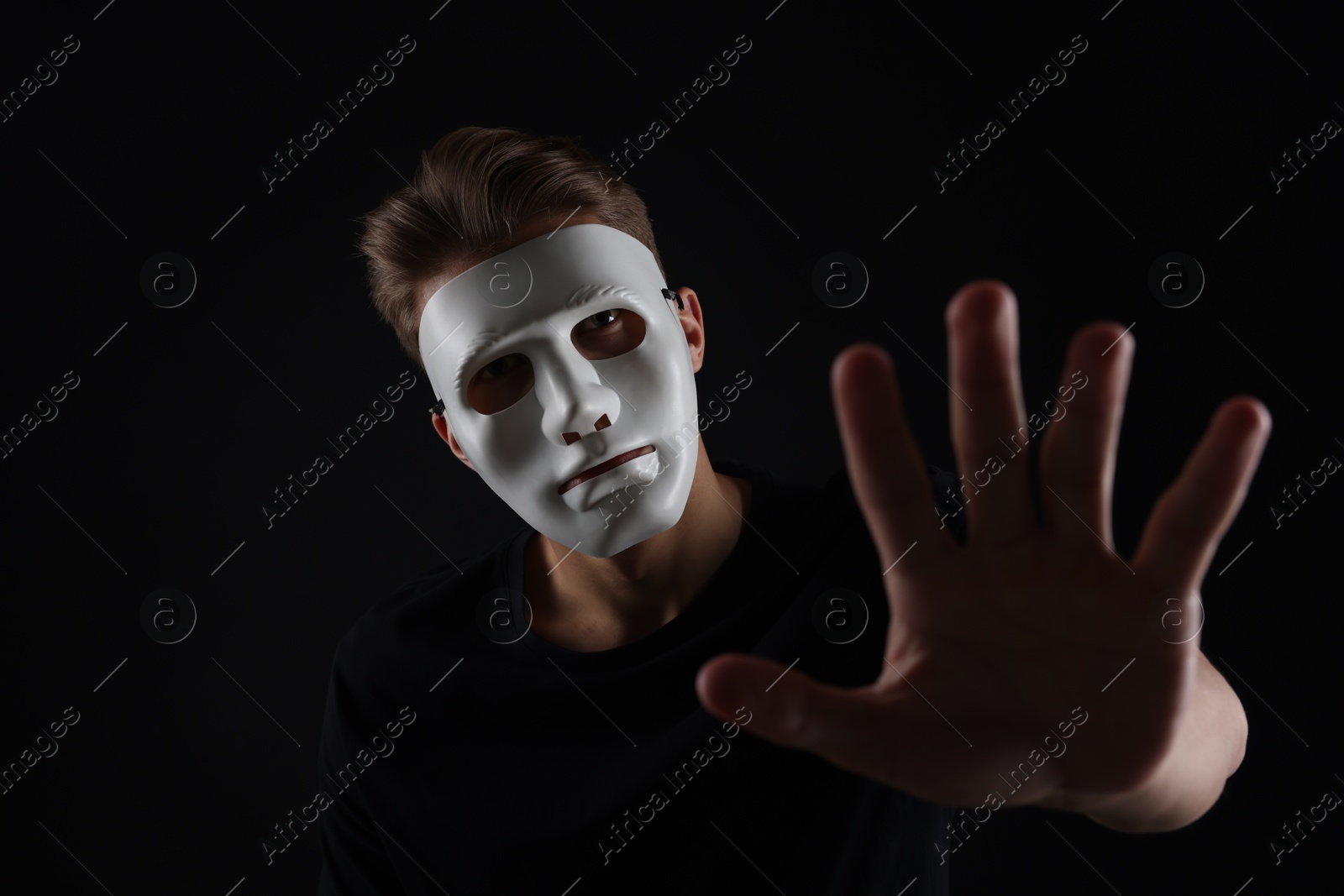 Photo of Anonymity. Man wearing mask on dark background