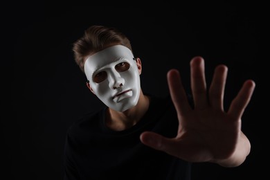 Photo of Anonymity. Man wearing mask on dark background