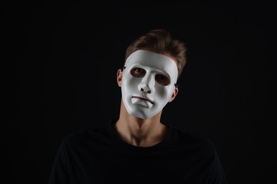 Photo of Anonymity. Man wearing mask on dark background