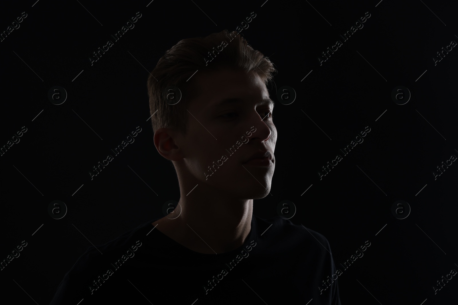 Photo of Anonymity. Portrait of young man in darkness