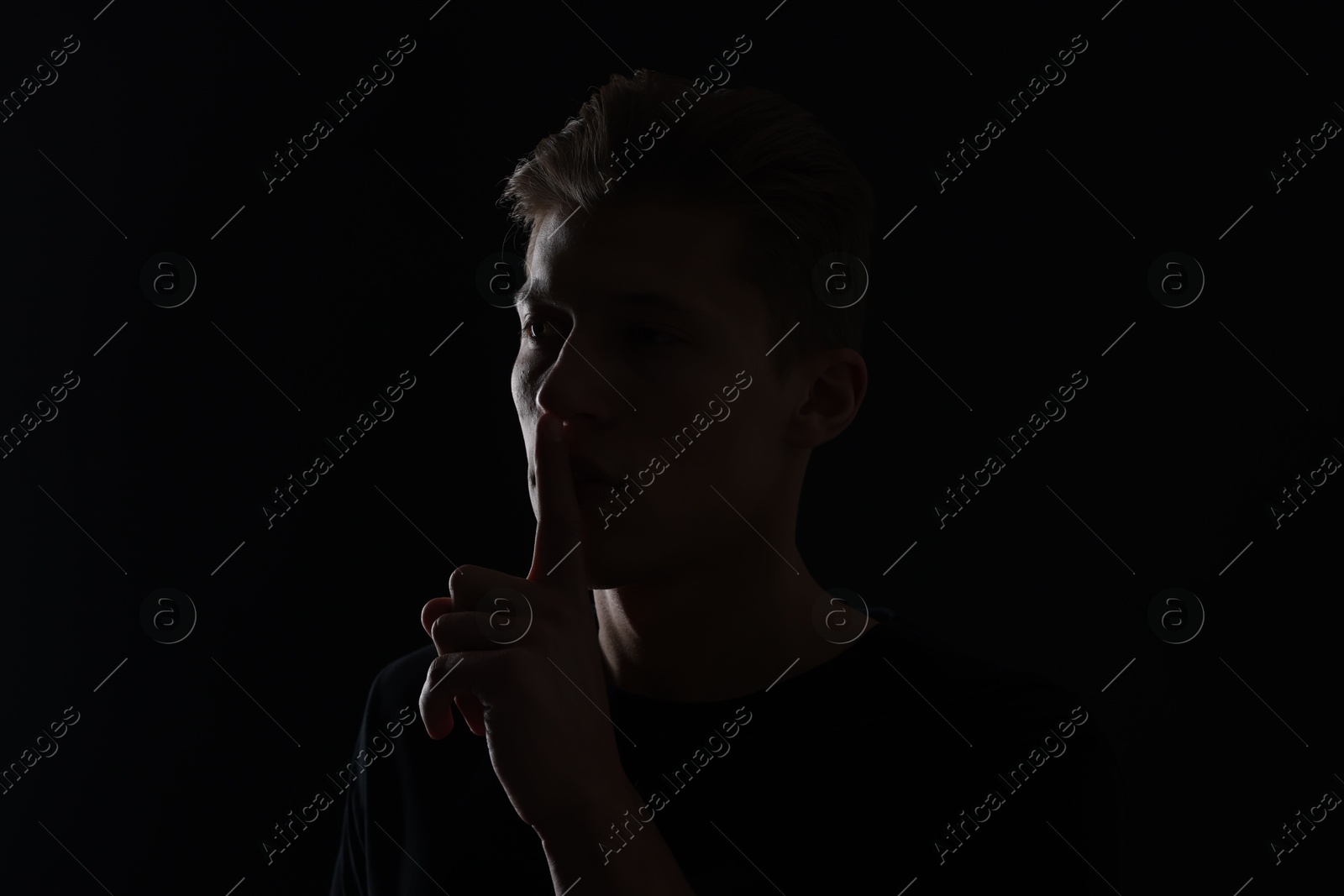Anonymity. Man showing silence gesture in darkness Photo of Anonymity. Man showing silence gesture in darkness