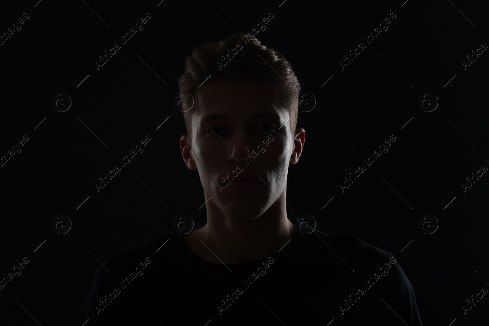 Photo of Anonymity. Portrait of young man in darkness