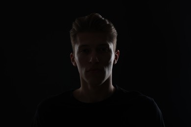 Photo of Anonymity. Portrait of young man in darkness