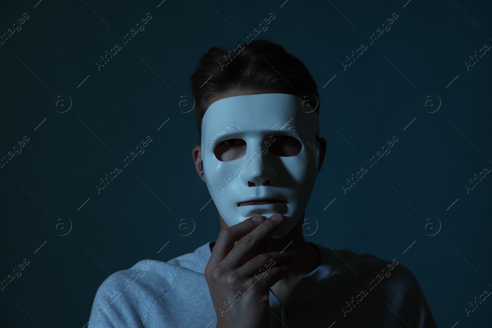 Photo of Anonymity. Man wearing mask on blue background