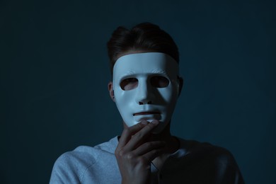 Photo of Anonymity. Man wearing mask on blue background