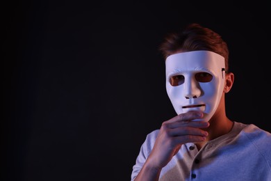 Photo of Anonymity. Man wearing mask on black background, space for text