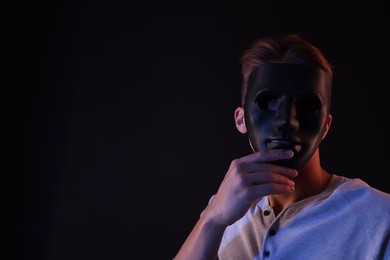 Photo of Anonymity. Man wearing mask on black background, space for text