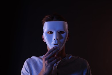 Photo of Anonymity. Man wearing mask on black background