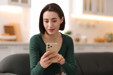 Photo of Woman using modern smartphone on sofa at home