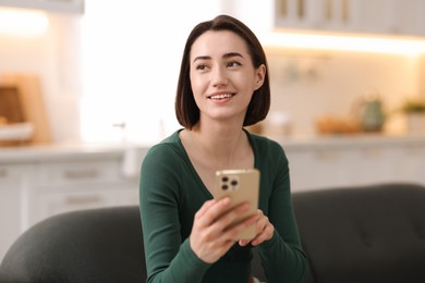 Photo of Woman using modern smartphone on sofa at home