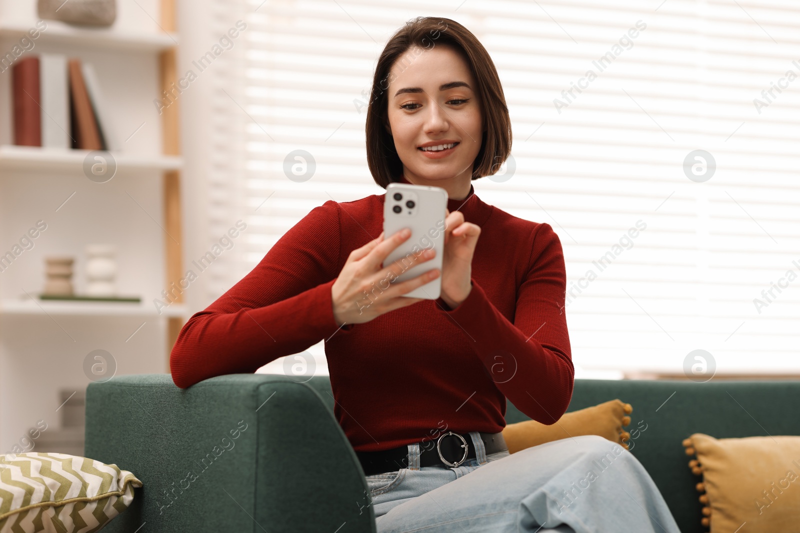 Photo of Woman using modern smartphone on sofa at home