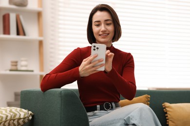 Photo of Woman using modern smartphone on sofa at home