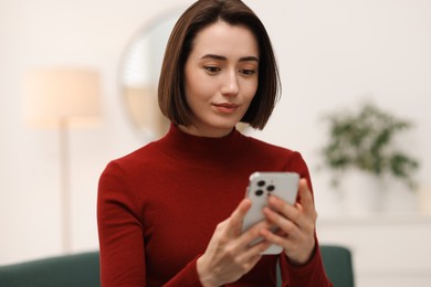 Photo of Woman using modern smartphone on sofa at home