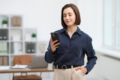Photo of Beautiful woman using her smartphone in office. Space for text