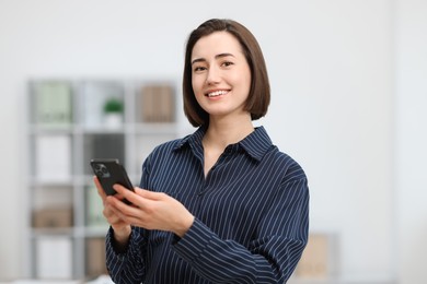 Photo of Beautiful woman using her smartphone in office