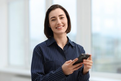 Photo of Beautiful woman using her smartphone in office