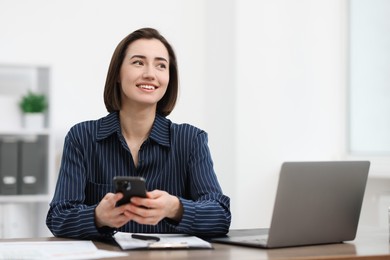 Photo of Beautiful woman using her smartphone while working at desk in office