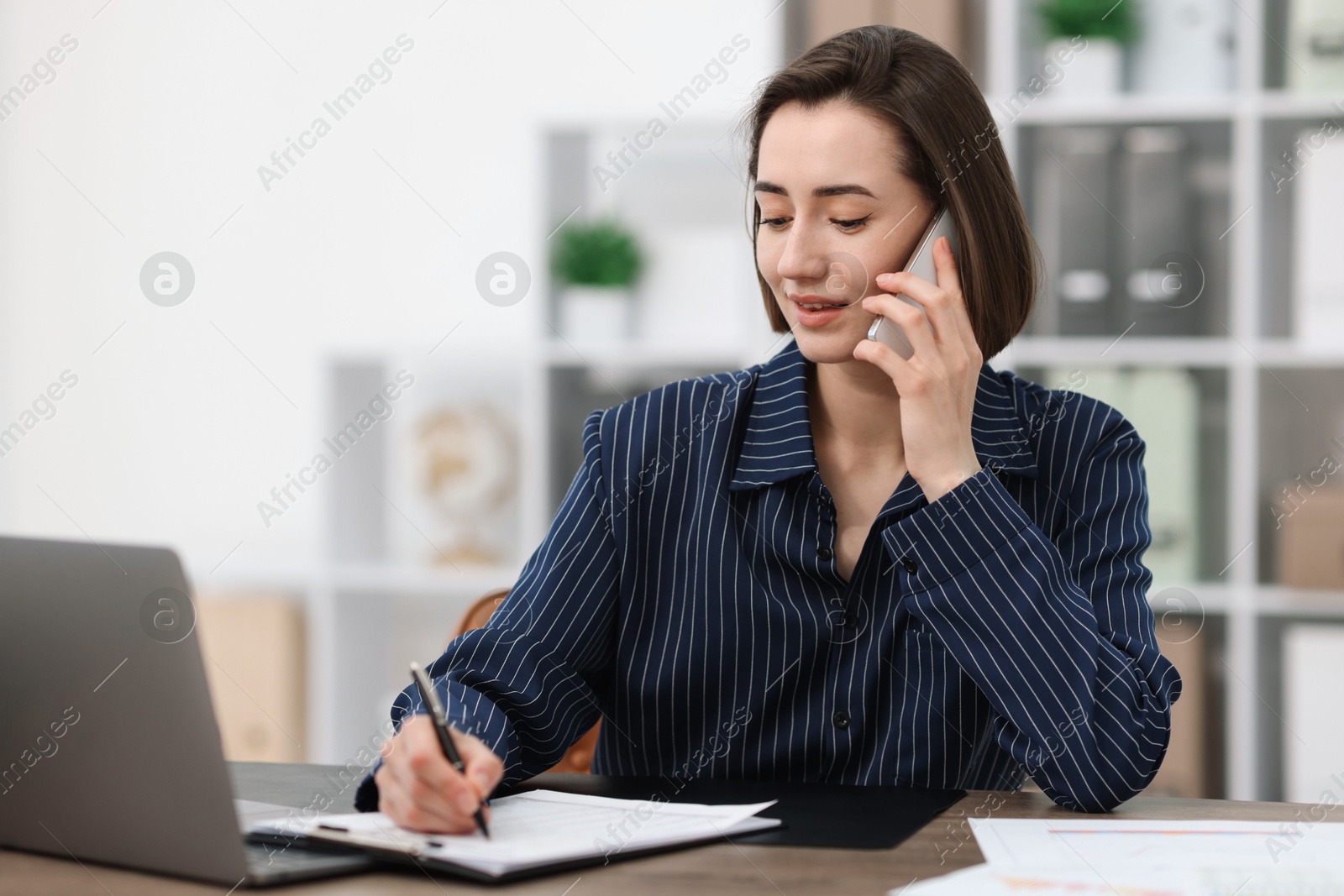 Photo of Beautiful woman talking on phone at desk in office. Space for text