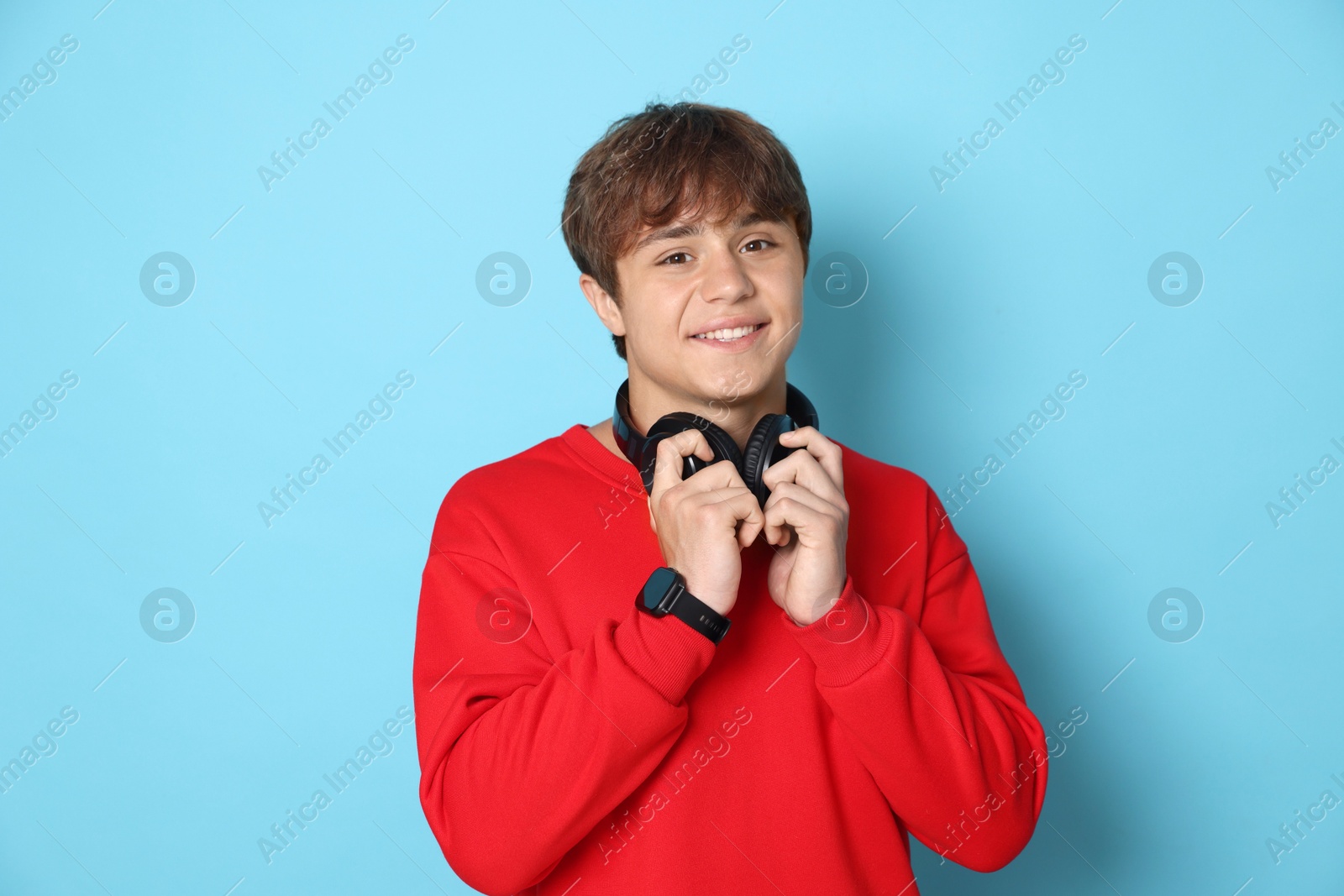 Photo of Portrait of smiling teenage boy with headphones on light blue background