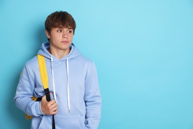 Photo of Cute teenage boy with backpack on light blue background. Space for text