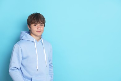 Photo of Portrait of cute teenage boy on light blue background. Space for text