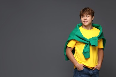Photo of Smiling teenage boy on grey background. Space for text