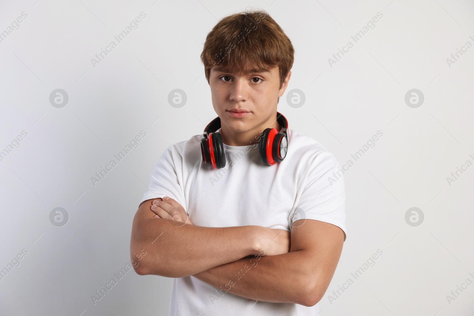 Photo of Portrait of cute teenage boy with crossed arms on light grey background
