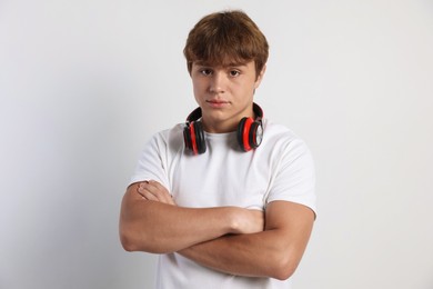 Photo of Portrait of cute teenage boy with crossed arms on light grey background