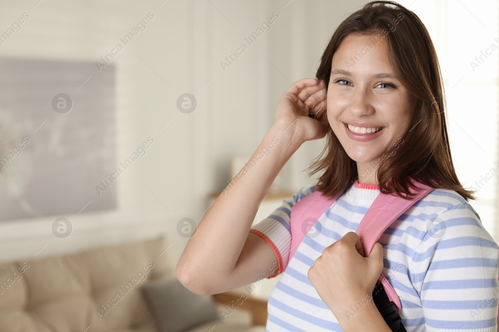Smiling teenage girl with backpack at home. Space for text Photo of Smiling teenage girl with backpack at home. Space for text