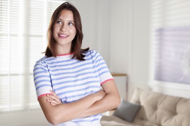 Photo of Smiling teenage girl with crossed arms at home
