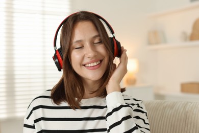 Photo of Portrait of smiling teenage girl in headphones at home