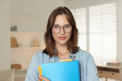 Photo of Portrait of beautiful teenage girl with notepads at home